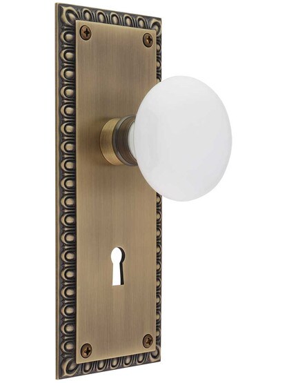 Ovolo Mortise-Lock Set with White Porcelain Knobs in Antique Brass.